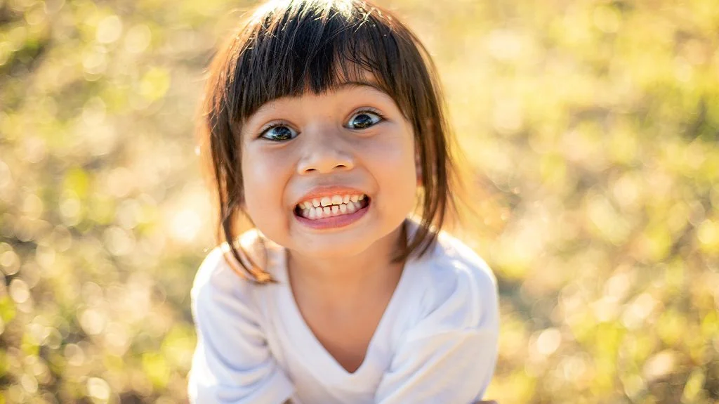 Kid showing her bite to indicate the importance of early orthodontic treatment and phase 1 treatment for kids